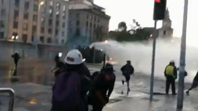 Chilenos se enfrentan a policías en Santiago; los disipan con tanquetas de agua