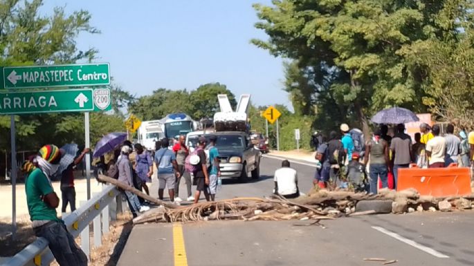 Migrantes realizan bloqueo para pedir “aventón”; transportistas  los desalojan con palos y piedras (Video)