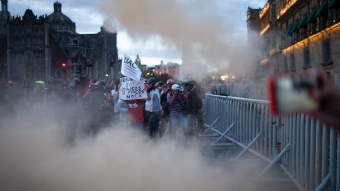 Encapuchados chocan con policías, lanzan vallas y queman una bandera tras marcha del 12 de octubre (Video)